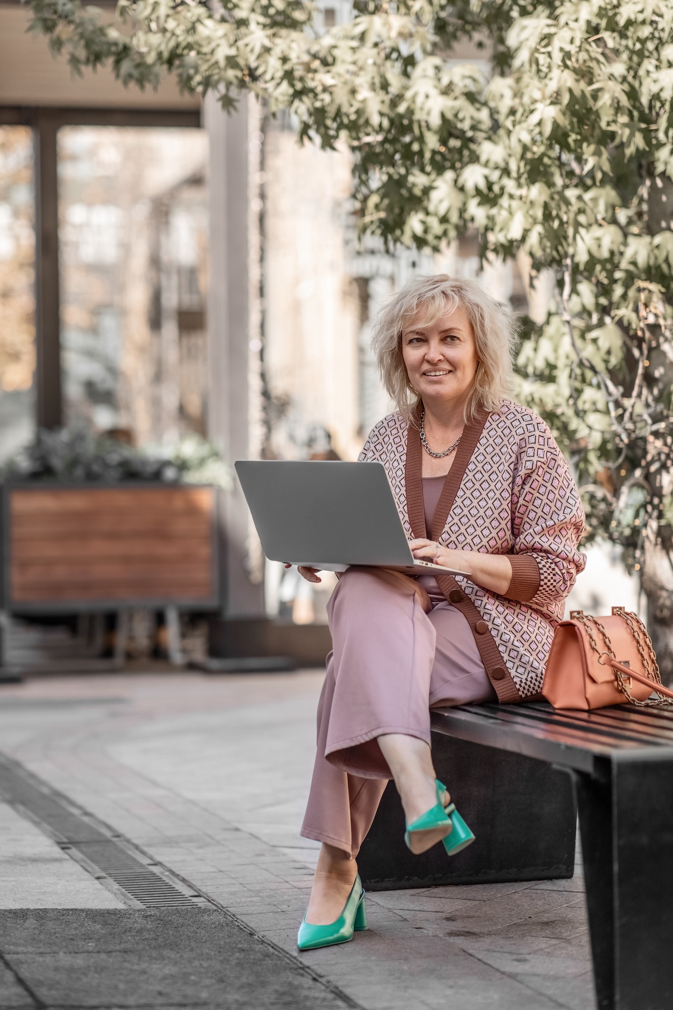 an adult blonde with a laptop conducts an online consultation sitting outdoors