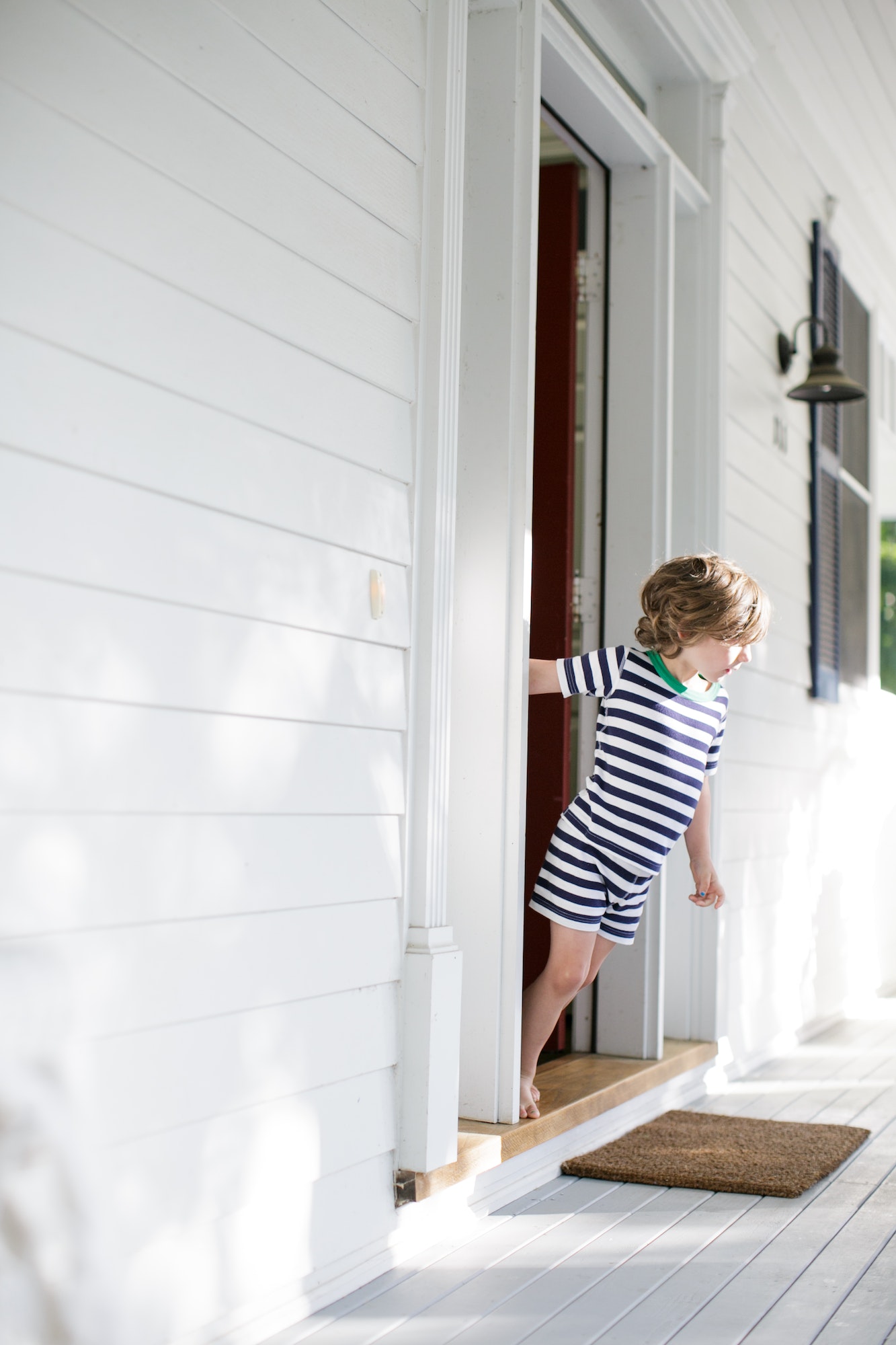 Boy leaning forward from front door onto porch